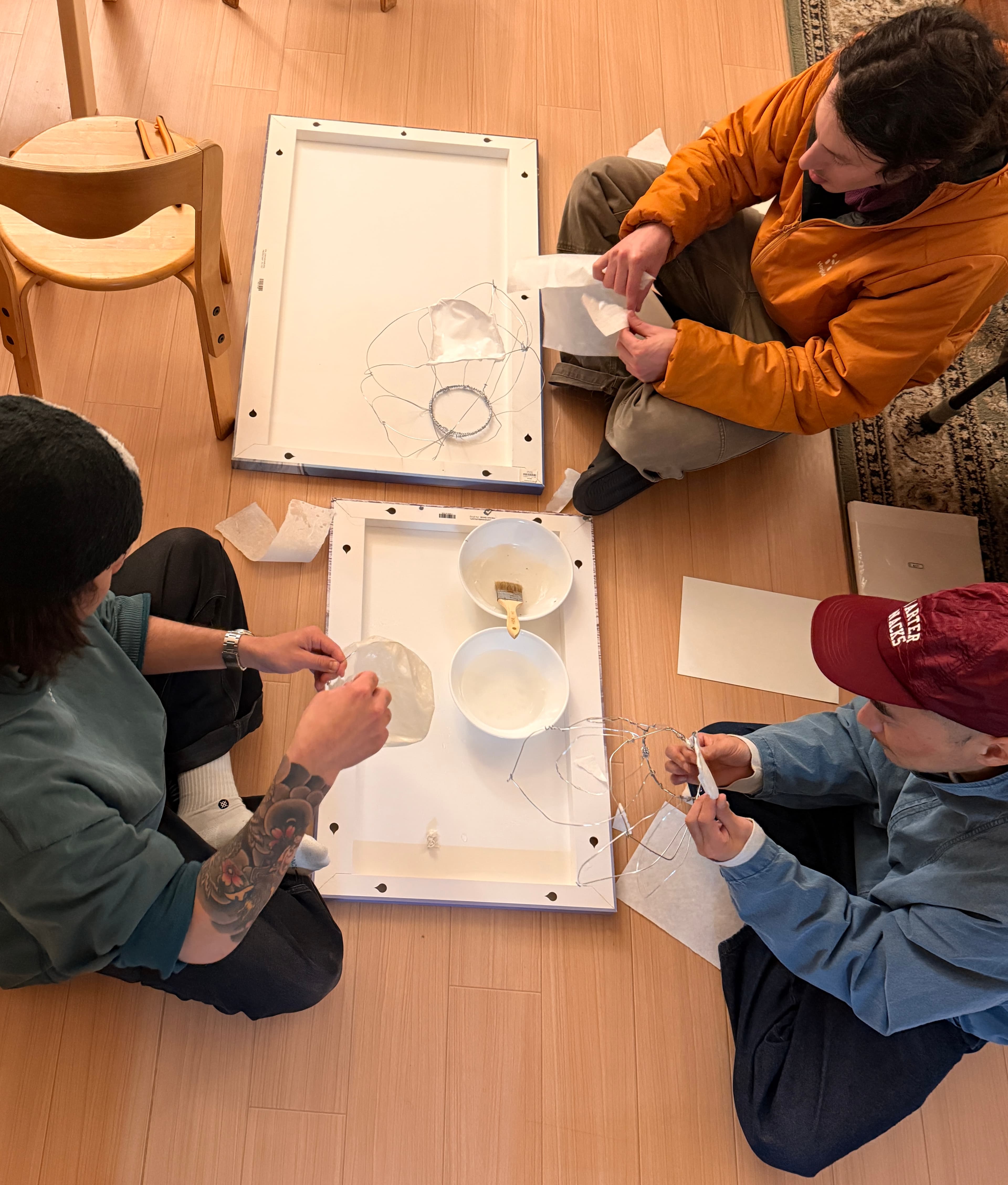 Guests sitting together on the floor, making and painting.