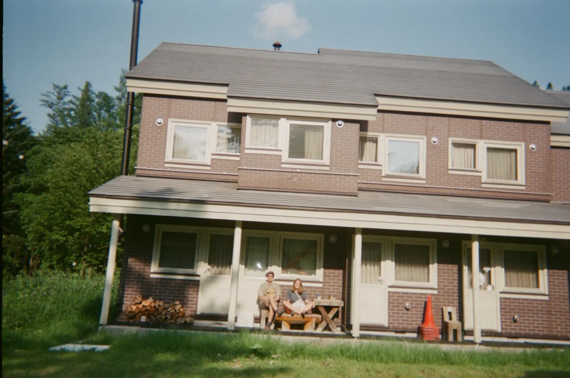 Denise and Riley sitting on the porch of Wakaranai Lodge with forest behind the building