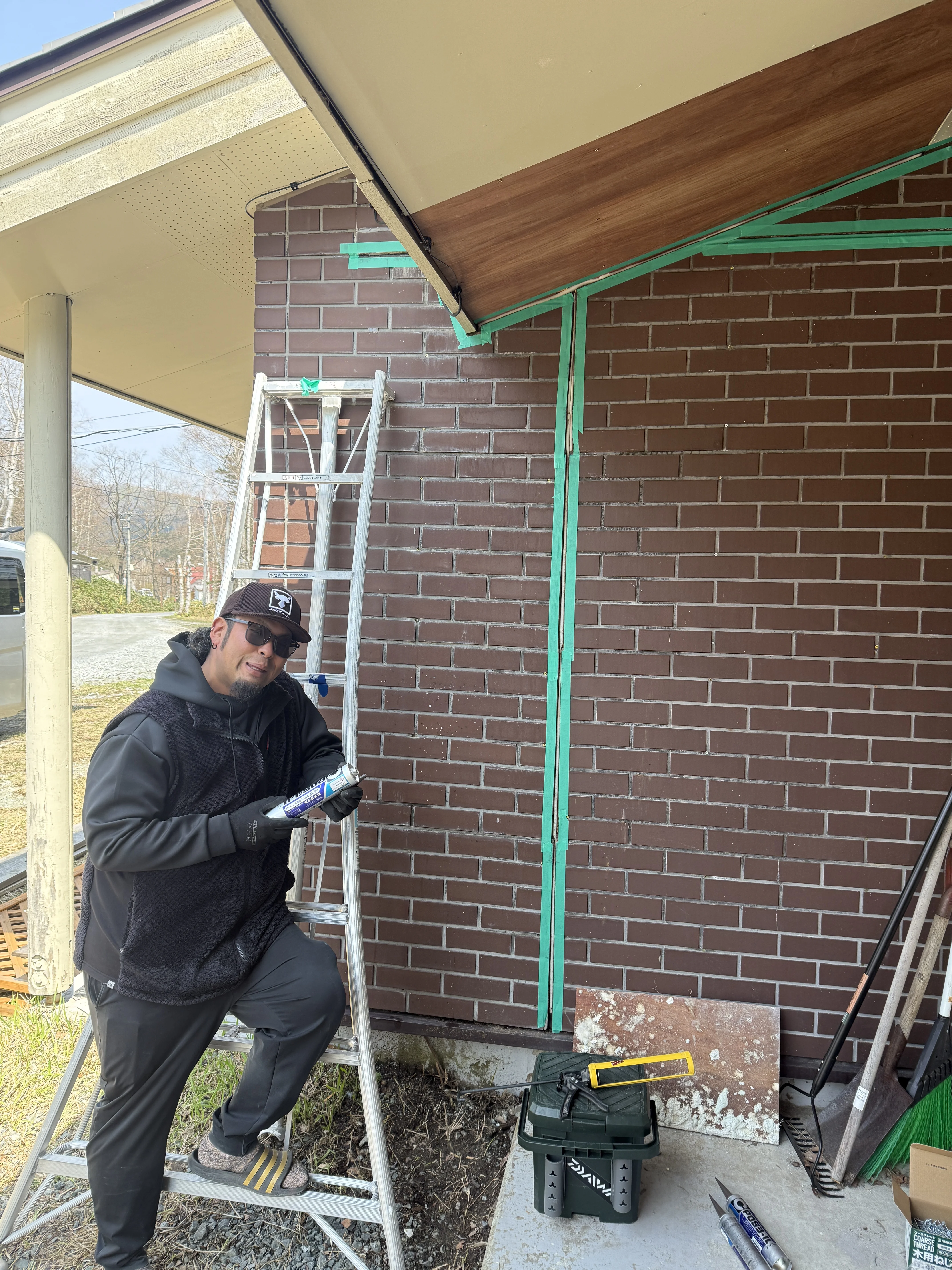 caulking prep on the brick exterior with ladder and sealant