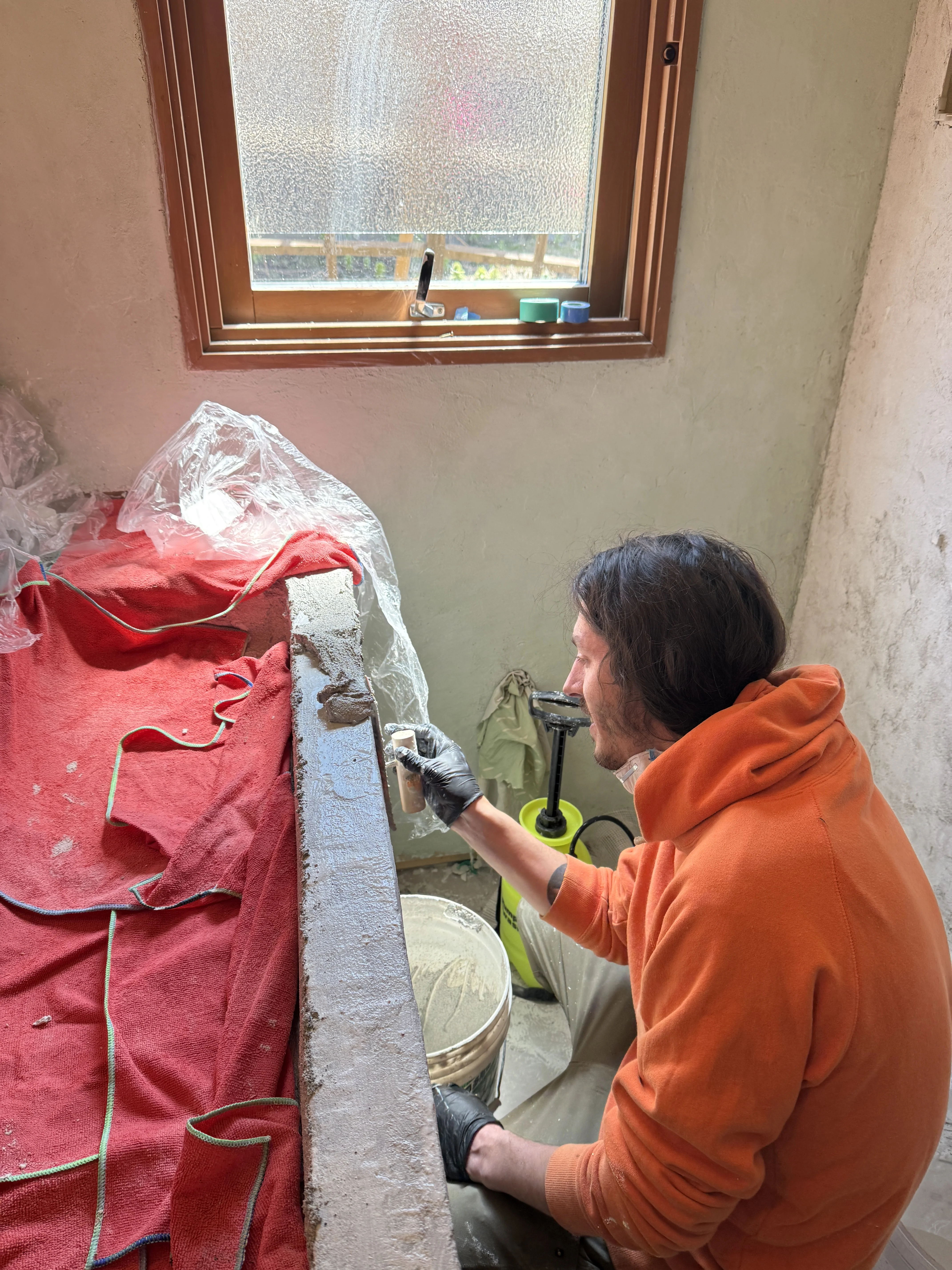 working on sink shaping layer by the bathroom window