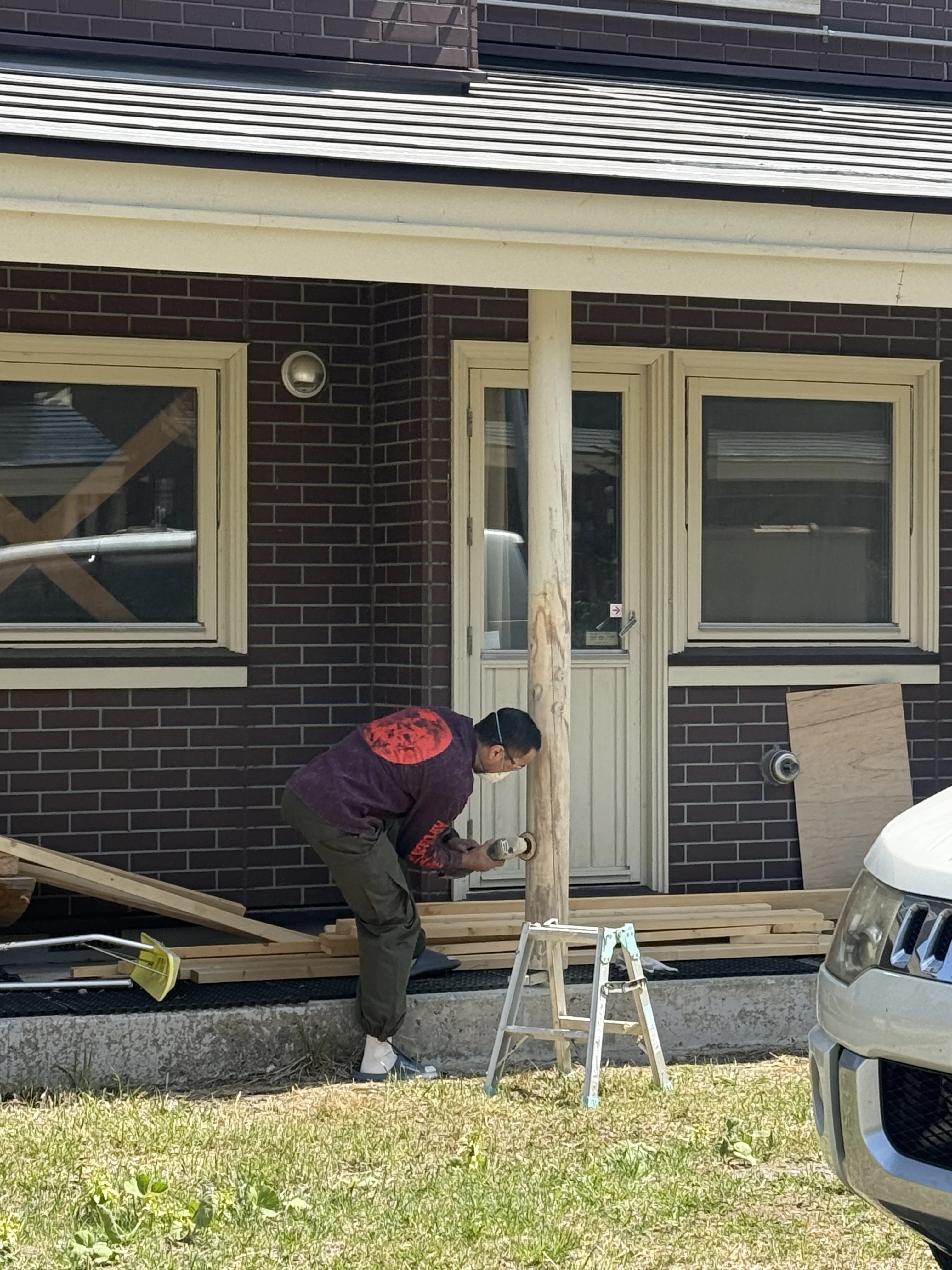 Akira sanding a porch support pole in front of the lodge
