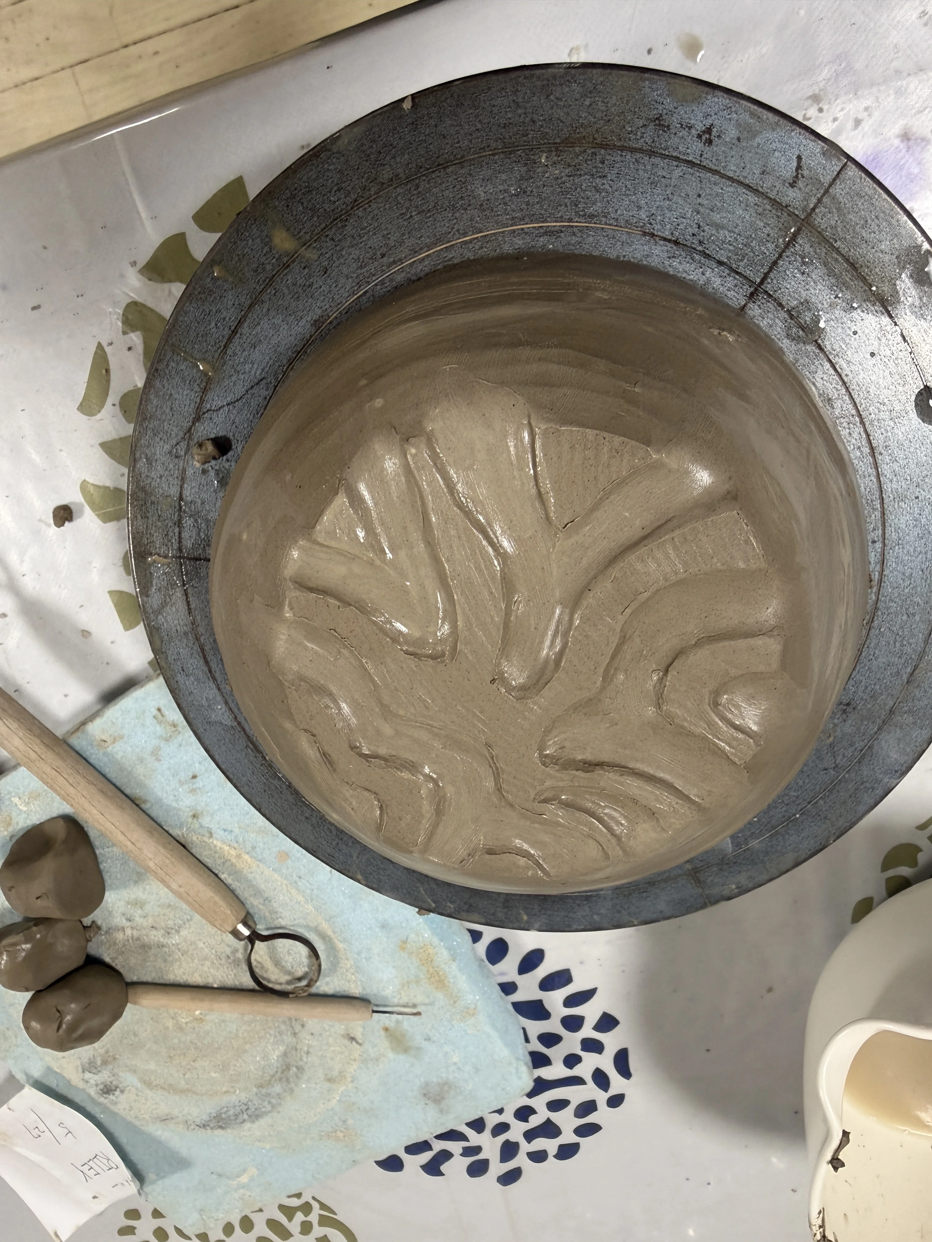 clay bowl with carved branching pattern on pottery wheel