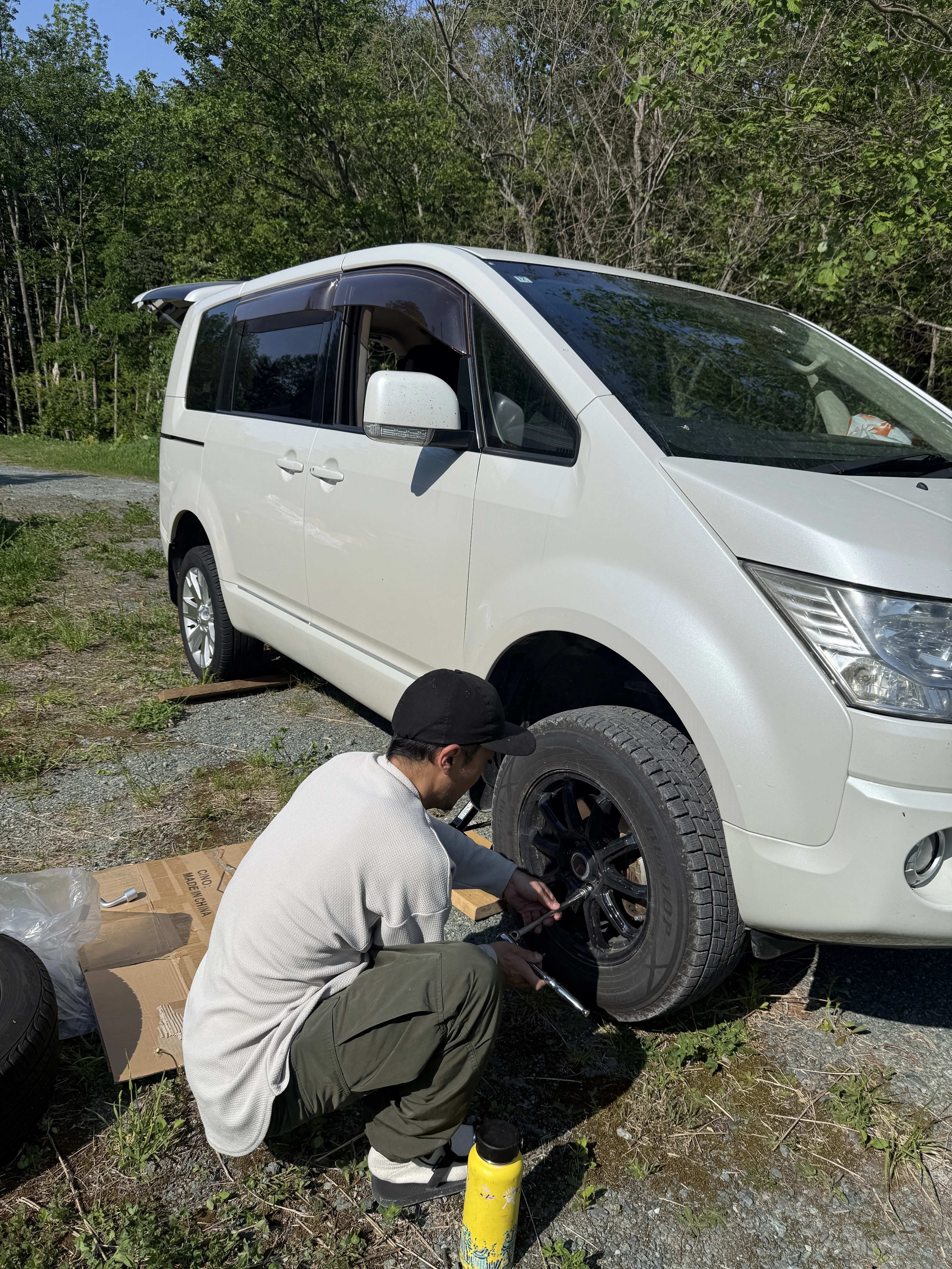 changing van tires with socket wrench on gravel driveway