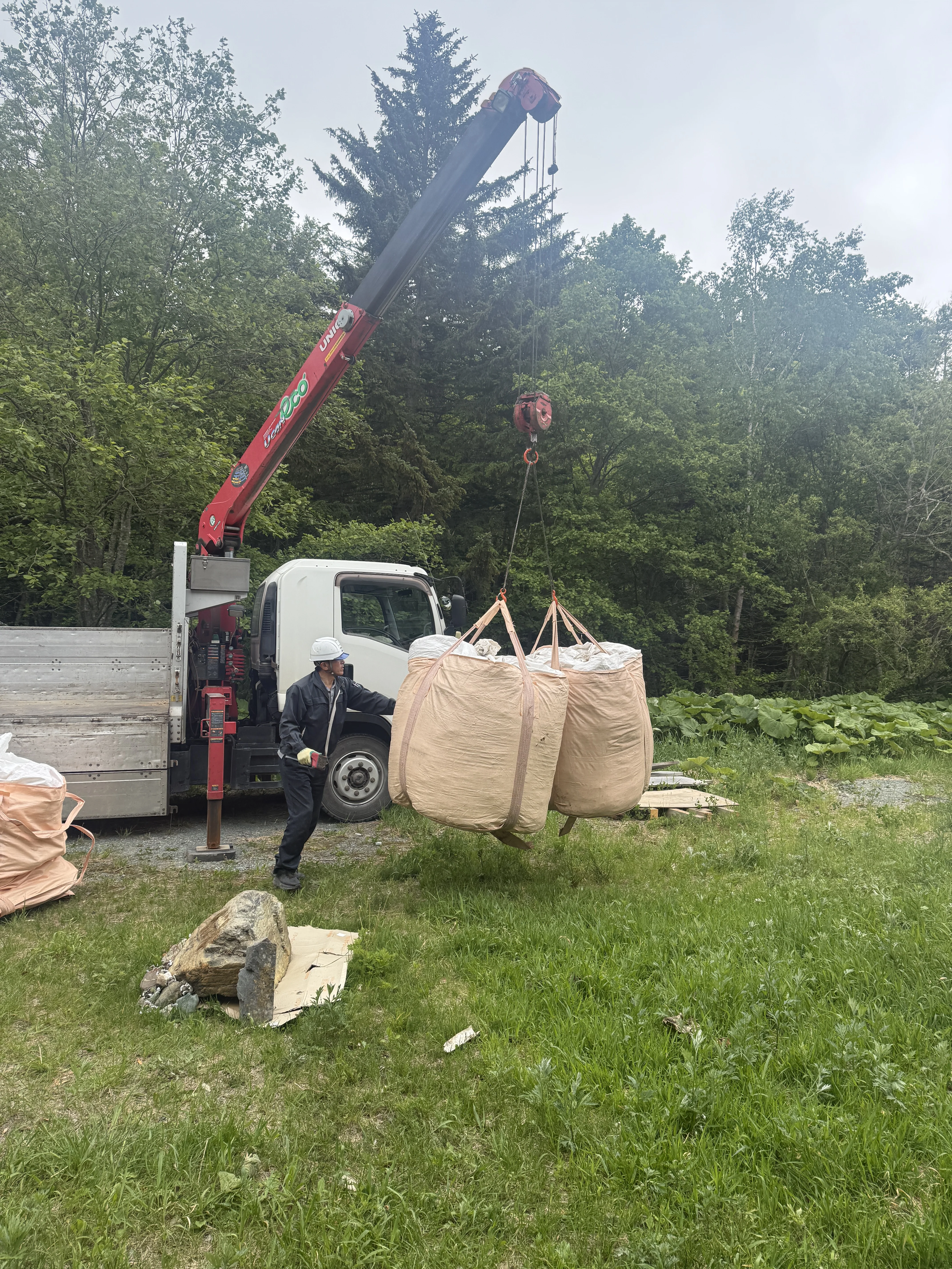 unic crane truck lowering woodchip ton bags in the yard